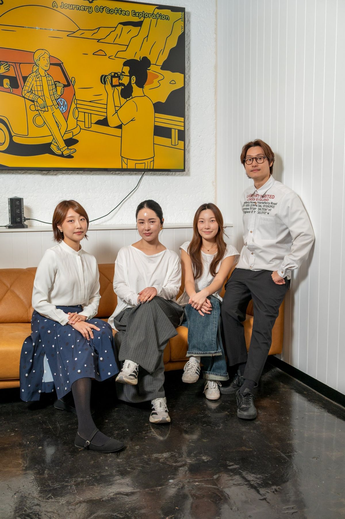 The Seoul Glow team on the tan leather sofa in the studio lounge, one standing against the white panelled wall